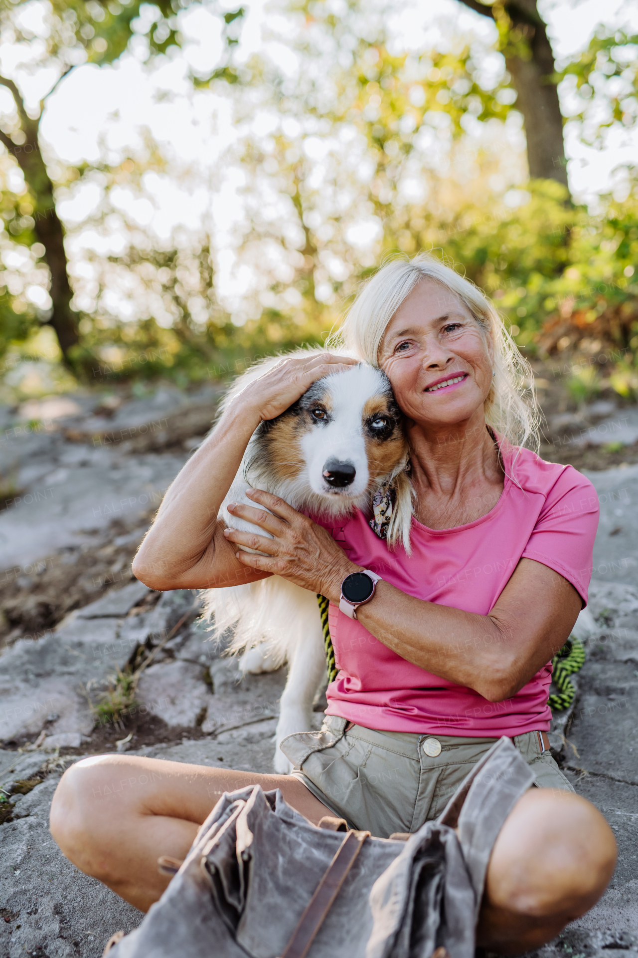 Portrait of senior woman with her dog in a forest.