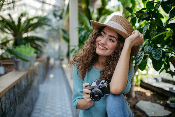 Portrait of young beautiful woman with camera in botanical garden.