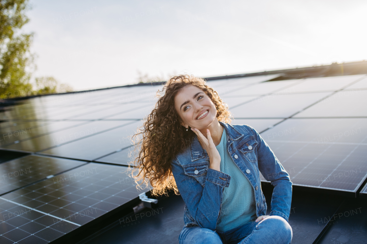 Portrait of young woman, owner on roof with solar panels.