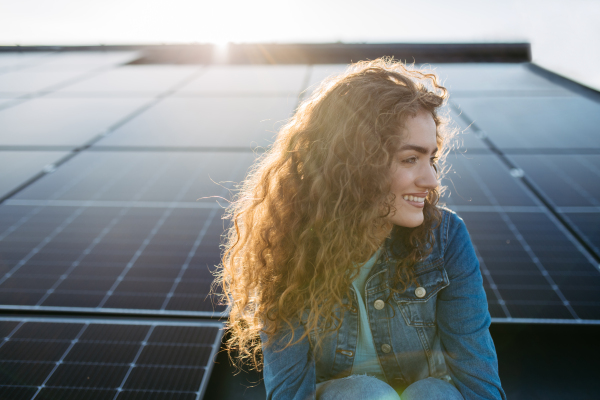 Portrait of young woman, owner on roof with solar panels.