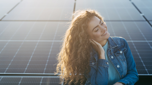 Portrait of young woman, owner on roof with solar panels.