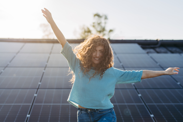 Portrait of young woman, owner on roof with solar panels.