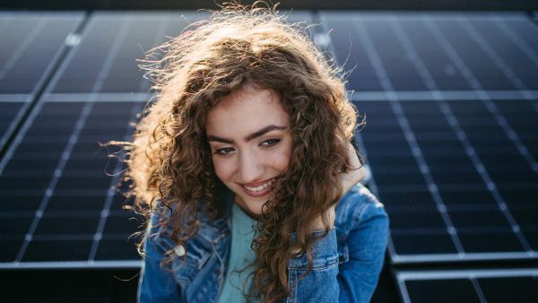 Portrait of young woman, owner on roof with solar panels.