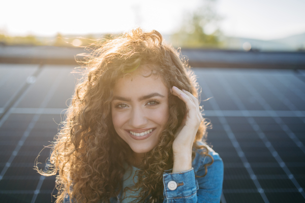 Portrait of young woman, owner on roof with solar panels.