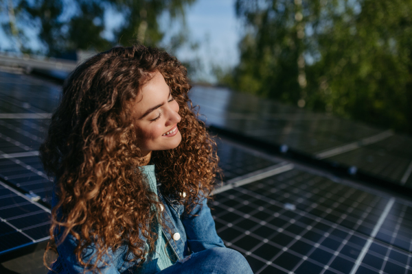 Portrait of young woman, owner on roof with solar panels.