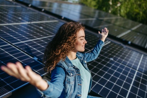 Portrait of young woman, owner on roof with solar panels.