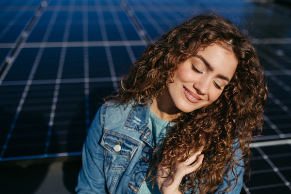 Portrait of young woman, owner on roof with solar panels.