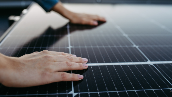 Close up of a woman touching solar panels on the roof.