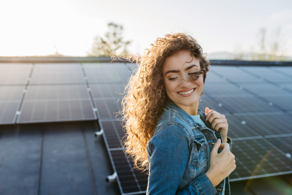 Portrait of young woman, owner on roof with solar panels.