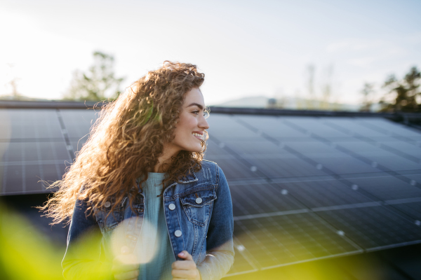 Portrait of young woman, owner on roof with solar panels.