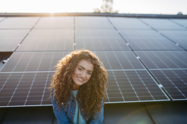 Portrait of young woman, owner on roof with solar panels.