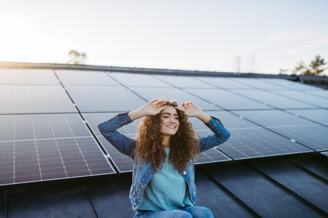 Portrait of young woman, owner on roof with solar panels.