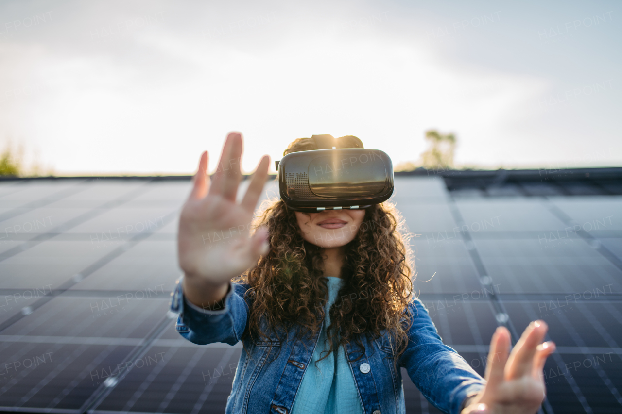 Young woman with virtual goggles on a roof with solar panels.