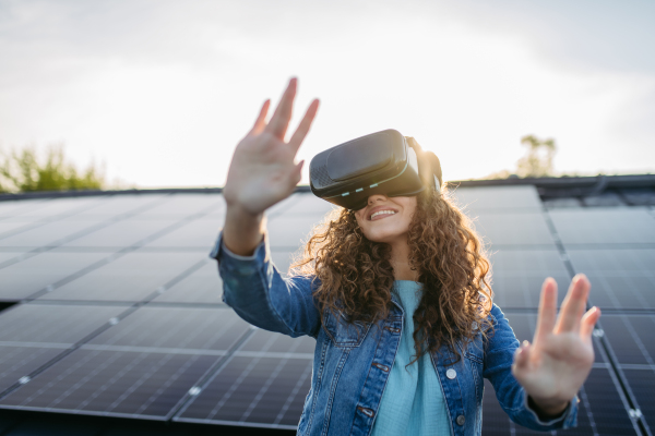 Young woman with virtual goggles on a roof with solar panels.