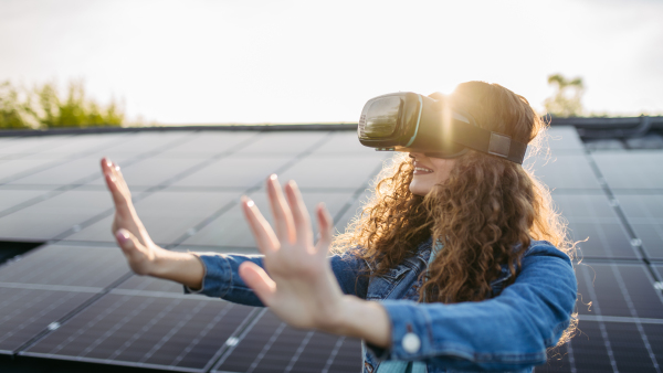 Young woman with virtual goggles on a roof with solar panels.