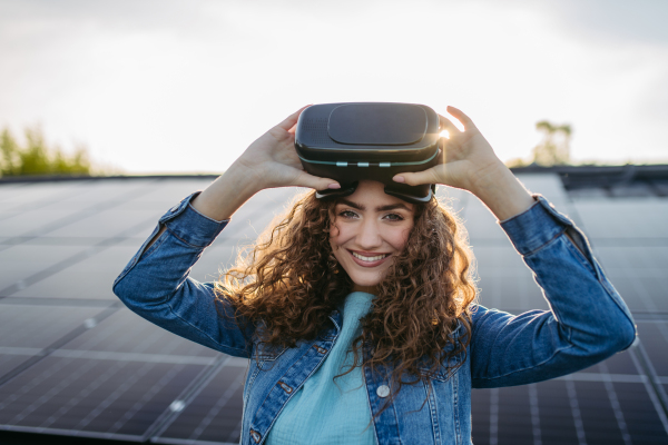 Young woman with virtual goggles on a roof with solar panels.