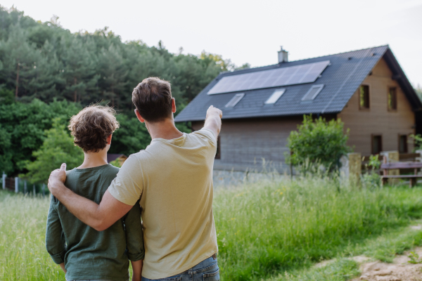 Father showing a roof with solar panels to his son. Alternative energy, saving resources and sustainable lifestyle concept.