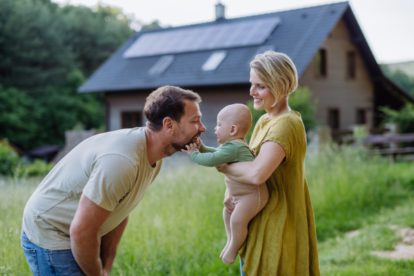 Happy family near their house with a solar panels. Alternative energy, saving resources and sustainable lifestyle concept.