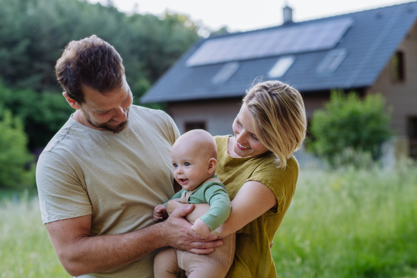 Happy family near their house with a solar panels. Alternative energy, saving resources and sustainable lifestyle concept.