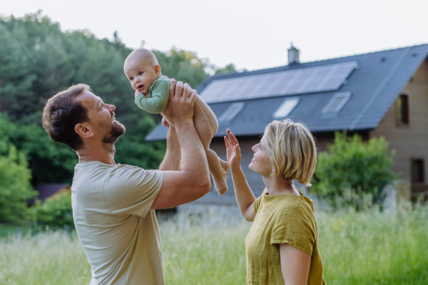 Happy family near their house with a solar panels. Alternative energy, saving resources and sustainable lifestyle concept.