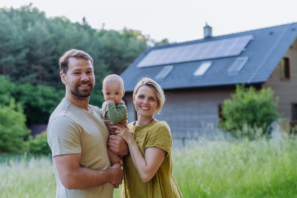 Happy family near their house with a solar panels. Alternative energy, saving resources and sustainable lifestyle concept.