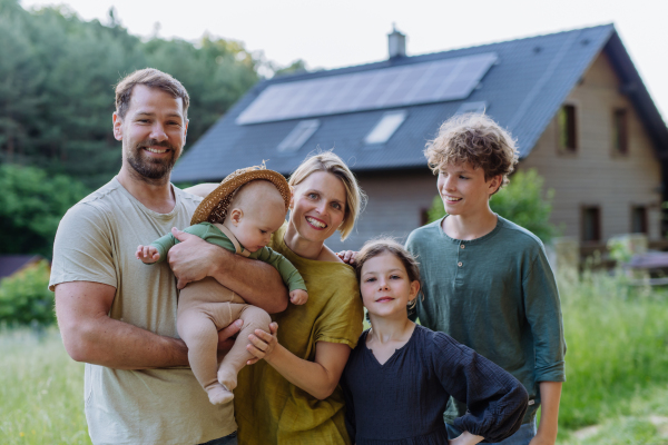 Happy family near their house with a solar panels. Alternative energy, saving resources and sustainable lifestyle concept.