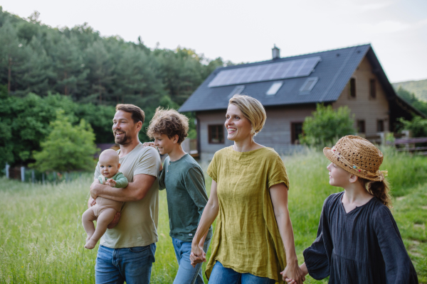 Happy family near their house with a solar panels. Alternative energy, saving resources and sustainable lifestyle concept.