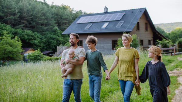 Happy family near their house with a solar panels. Alternative energy, saving resources and sustainable lifestyle concept.