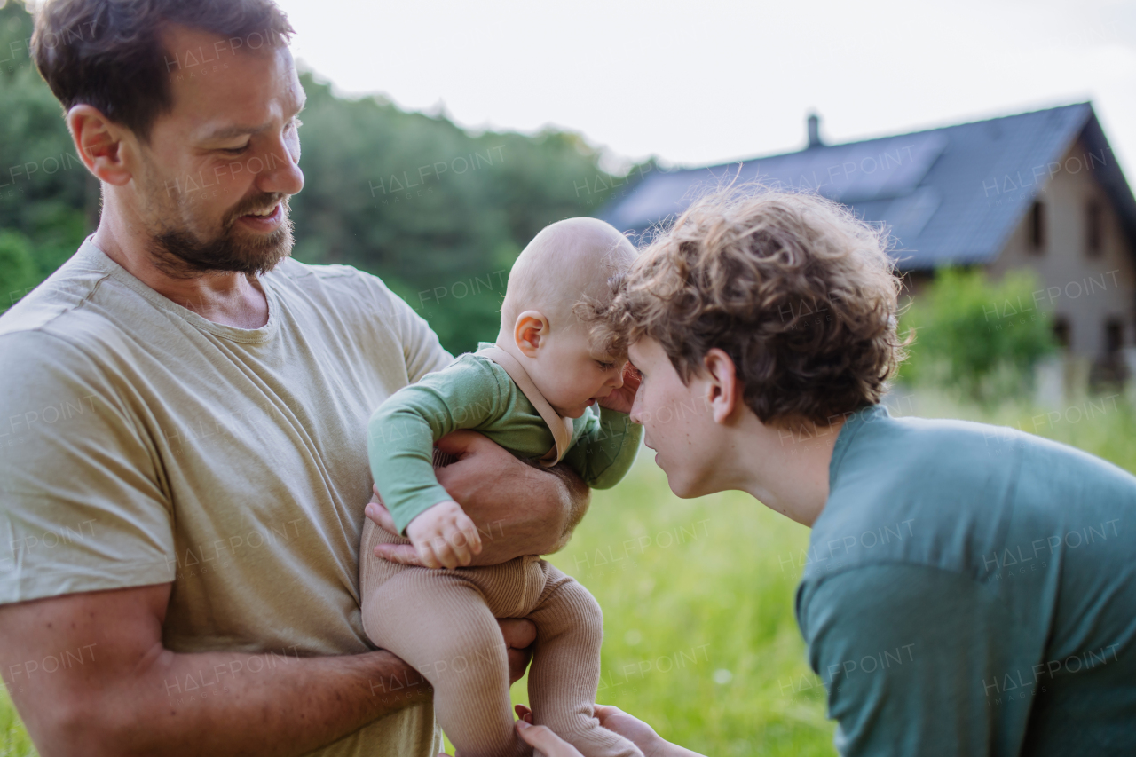 Happy father with baby boy standing in front of their house with solar panels.