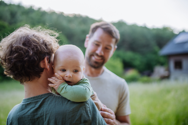 Happy father with baby boy standing in front of their house with solar panels.