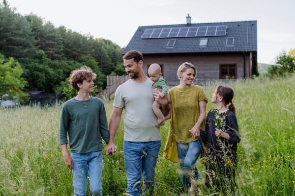 Happy family near their house with a solar panels. Alternative energy, saving resources and sustainable lifestyle concept.