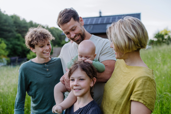 Happy family near their house with a solar panels. Alternative energy, saving resources and sustainable lifestyle concept.