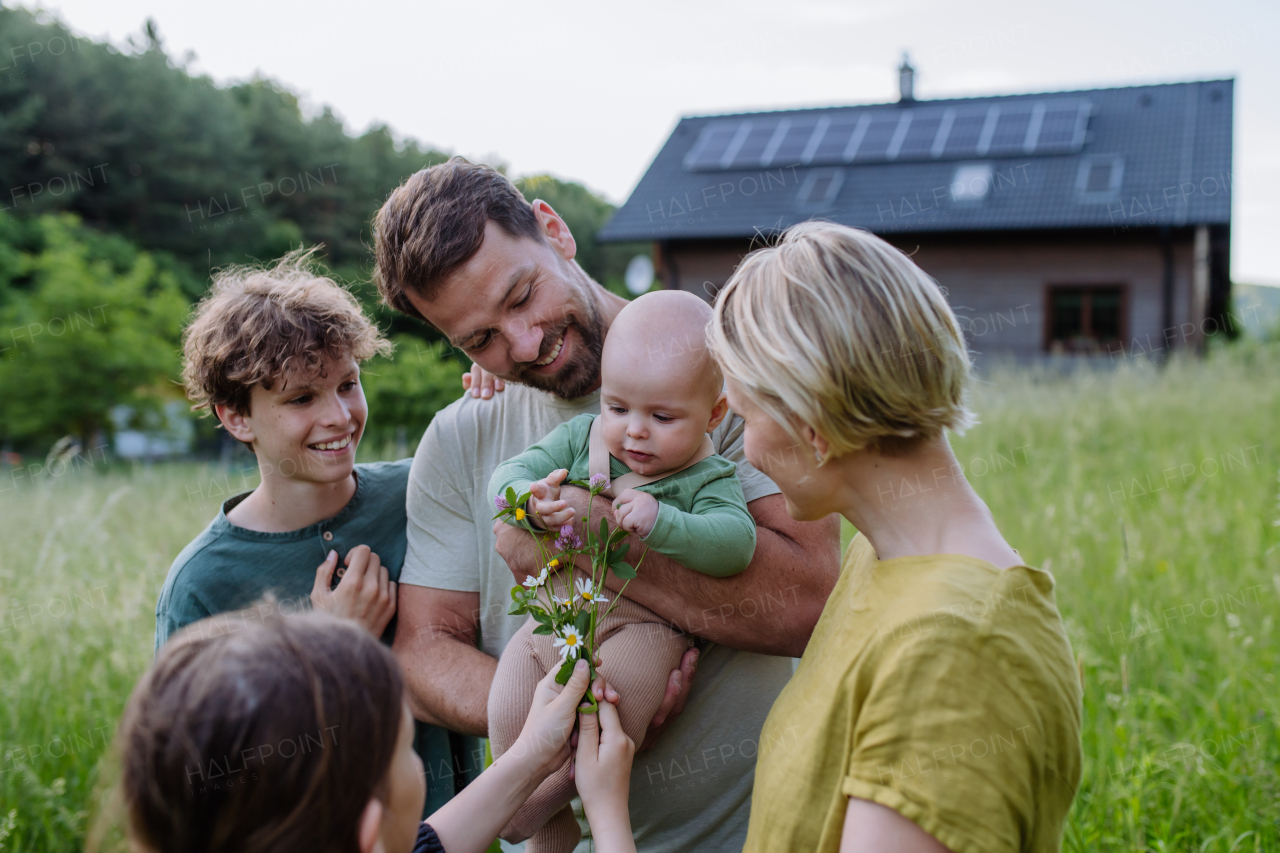 Happy family near their house with a solar panels. Alternative energy, saving resources and sustainable lifestyle concept.