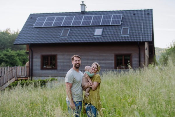 Happy family near their house with a solar panels. Alternative energy, saving resources and sustainable lifestyle concept.