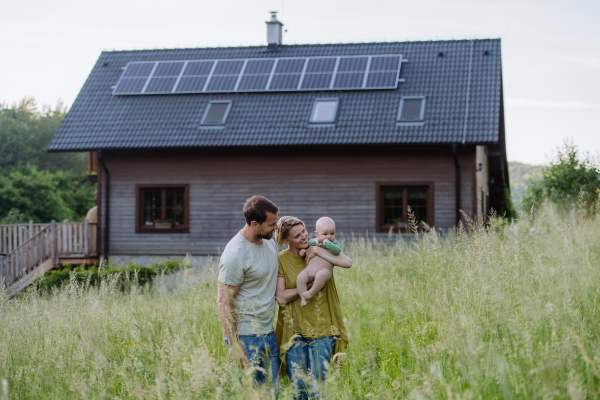 Happy family with baby near their house with a solar panels. Alternative energy, saving resources and sustainable lifestyle concept.