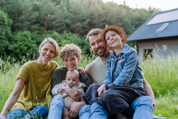 Happy family near their house with a solar panels. Alternative energy, saving resources and sustainable lifestyle concept.