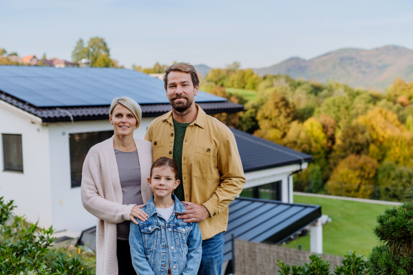 Happy family near their house with a solar panels. Alternative energy, saving resources and sustainable lifestyle concept.