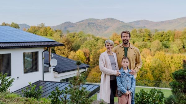 Happy family near their house with a solar panels. Alternative energy, saving resources and sustainable lifestyle concept.