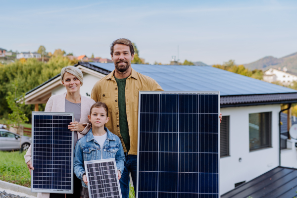 A happy family near their house with solar panel. Alternative energy, saving resources and sustainable lifestyle concept.