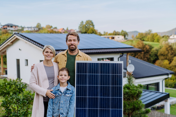 A happy family near their house with solar panel. Alternative energy, saving resources and sustainable lifestyle concept.