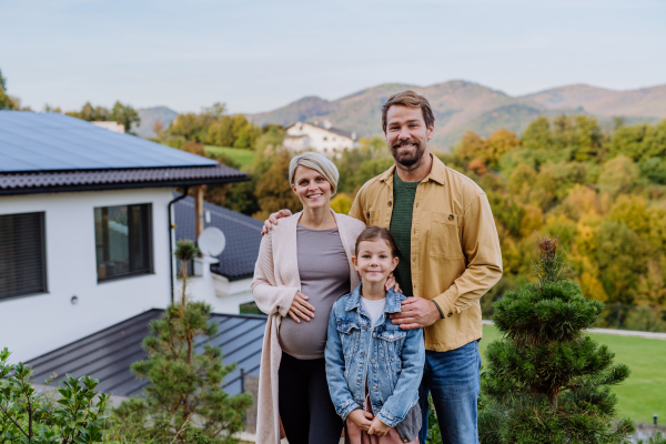 Happy family near their house with a solar panels. Alternative energy, saving resources and sustainable lifestyle concept.