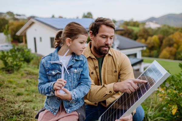 Father showing his little daughter solar photovoltaics panels, explaining how it working. Alternative energy, saving resources and sustainable lifestyle concept.