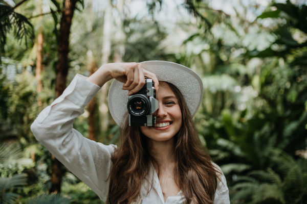 Portrait of a young woman with camera in jungle.