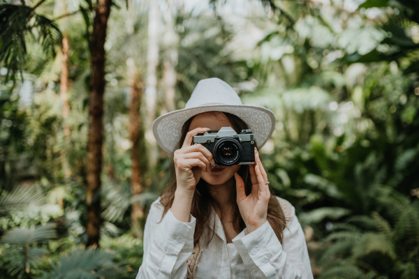 Portrait of a young woman with camera in jungle.