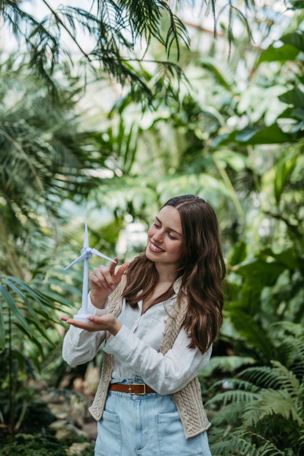 Portrait of a young woman with wind turbine in jungle.