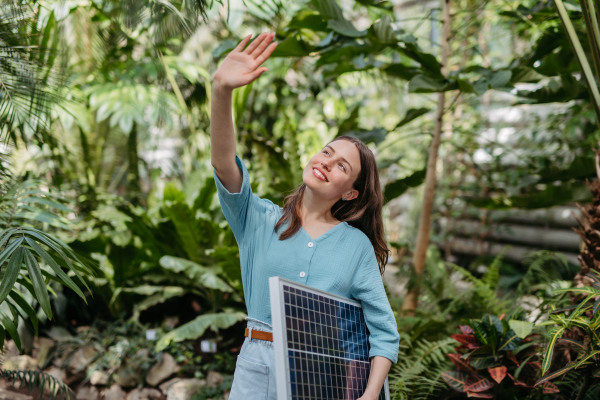 Young woman in botanical garden with a photovoltaics panel.