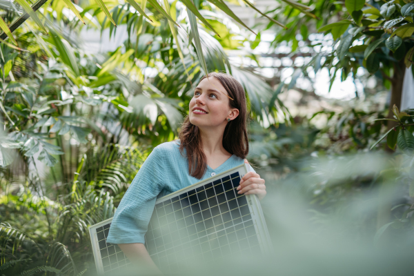 Young woman in botanical garden with a photovoltaics panel.