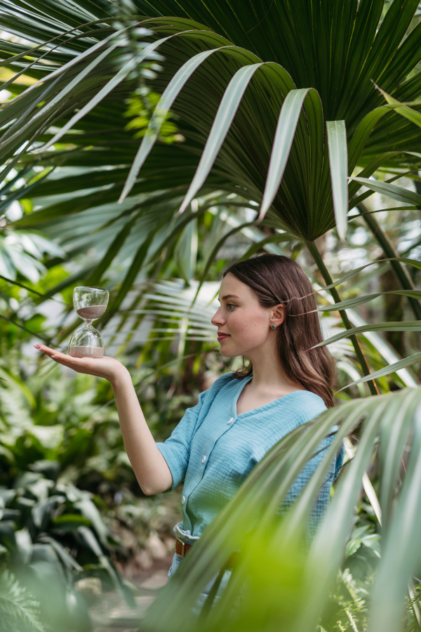 Young woman with a hourglass in jungle, concept of nature protection.