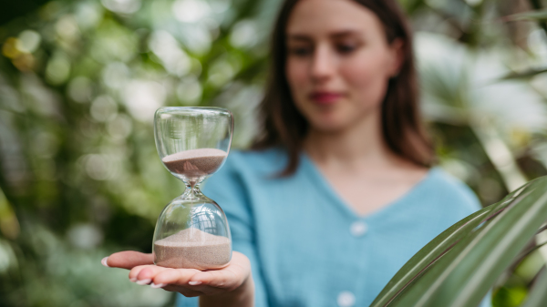 Young woman with a hourglass in jungle, concept of nature protection.