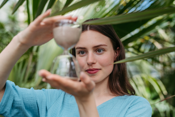 Young woman with a hourglass in jungle, concept of nature protection.